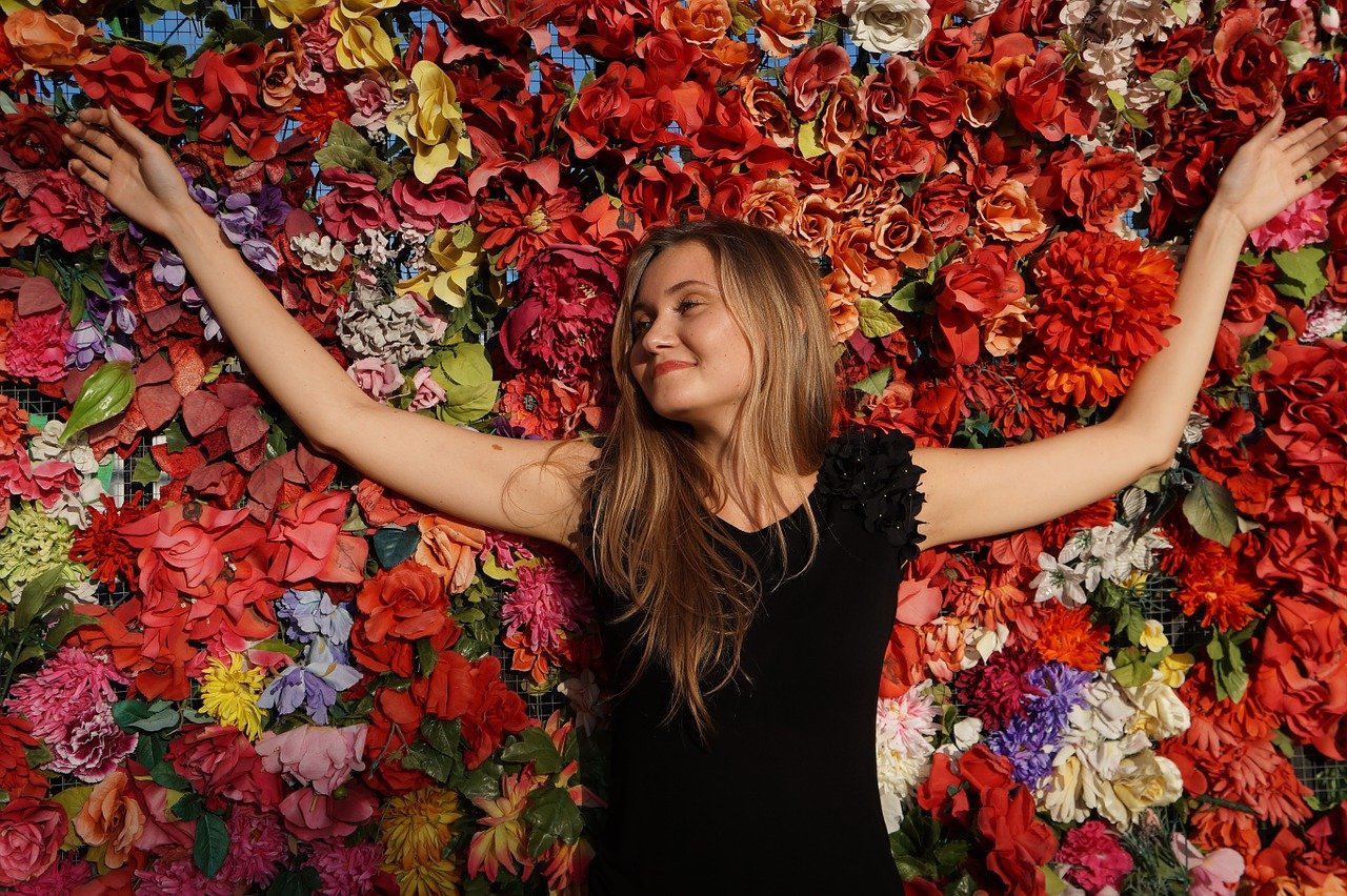 Woman standing in front of a wall of colorful flowers